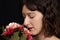 Young brunette woman smelling bouquet of rosy and red flowers