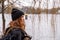 Young brunette woman standiing by a lake on snowy day looking pensive