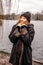 young brunette woman standing outdoors by a lake on snowy day and is freezing