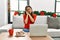 Young brunette woman using laptop sitting on the sofa on christmas sleeping tired dreaming and posing with hands together while