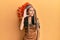 Young brunette woman wearing indian costume smiling with hand over ear listening an hearing to rumor or gossip