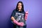 Young brunette woman wearing volunteer t-shirt picking plastic bottles over purple background surprised with an idea or question