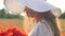 Young brunette woman in white dress and big hat stands in the middle of the field of poppies. Charming lady with