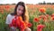 Young brunette woman in white dress stands in the middle of the field of poppies. Charming lady with incredible smile