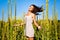 Young brunette woman in white mini dress standing with eyes closed and enjoying sunshine in high grass on summer day