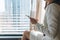 Young brunette woman in white suit with mobile in hotel room or office on high floor