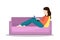 Young brunette woman working on laptop lying on sofa. Concept of working from home