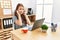 Young brunette woman working at the office with laptop covering ears with fingers with annoyed expression for the noise of loud