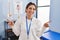 Young brunette woman working at pain recovery clinic smiling confident pointing with fingers to different directions