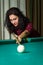 Young brunnete woman aiming to ball playing billiard.