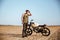 Young brutal man in black standing near a motorcycle