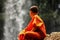 Young buddhist Monk is dreaming at the Waterfall