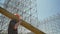 Young builder in helmet transferring heavy metal plank, working near huge metal installation