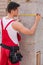 Young builder measuring wall