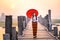 A young Burmese woman is walking with a red umbrella on the longest teak bridge in Asia.U-bein bridge, Mandalay, Myanmar.