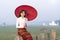 A young Burmese woman is walking with a red umbrella on the longest teak bridge in Asia. U-bein bridge  Mandalay  Myanmar. Space