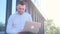 A young business freelancer works with a laptop on the street near an office center.