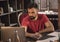 Young business man with beard sitting at table with laptop in cozy dark office