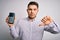 Young business man with blue eyes holding dataphone payment terminal over isolated background with angry face, negative sign