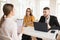 Young business man with laptop and business woman in eyeglasses talking with applicant about work. Young smiling