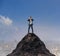 Young business man standing on top of mountain and spying by bin