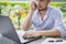 Young business man talking on phone working with laptop computer outdoor. Business freelance using laptop and mobile phone working