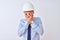 Young business man wearing contractor safety helmet over isolated background with sad expression covering face with hands while