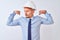 Young business man wearing contractor safety helmet over isolated background showing arms muscles smiling proud