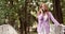 Young business woman with bright red hair is standing on a white bridge in summer park.