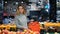 Young business woman girl buyer client blonde lady consumer stands in shop near counter with fruits in grocery store