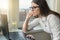 Young business woman with glasses working on laptop computer at home, in hotel, talking on video, working remotely