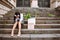 Young business woman in office siut sitting on stairs with a box of her office supplies and sign looking for a job. Unemployment