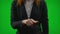 Young business woman searching information on virtual dashboard sliding and zooming with fingers against green screen -