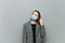 Young business woman stands on a gray background and removes a protective mask from her face
