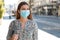 Young business woman with surgical mask waiting bus on bus stop in city street