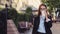 Young business woman is walking on the street and drinks coffee and using smartphone at lunch break.