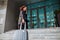 Young business woman walking up the staircase with a suit ready to check in at hotel`s reception. Beginning of a