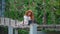 Young business women with thick beautiful fiery red hair sits on suspension bridge over river and works on laptop