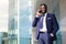 Young businessman with a beard in blue suit speaking on the phone outside with copy space