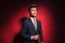 Young businessman in black with red tie arranging his jacket