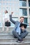 Young businessman celebrating success with hand in the air, working on a tablet in front of an office building