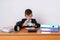 Young businessman is counting profit. On the table is a calculator, next to a mini shopping trolley, a clock and folders with