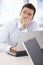 Young businessman daydreaming at desk