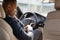 Young businessman driver sitting inside car fastening belt back seat view