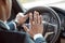 Young businessman driver sitting inside car holding steering wheel pushing horn back view close-up