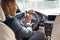 Young businessman driver sitting inside pushing horn smiling cheerful car back seat view