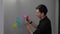 young businessman employee retiring and removing sticky notes off of the wall, cleaning office room after a business meeting,