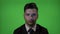 Young businessman entrepreneur working in IT industry having a hologram programming code on face on a green screen background -