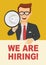 Young businessman with glasses speaking with megaphone pointing to blank board with we are hiring text