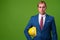 Young businessman with hardhat against green background
